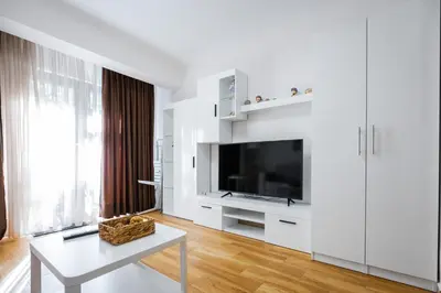 a white living room with a tv and a table at 1BD Elegance on Vasil Levski Boulevard by Flat Mаnager in Sofia
