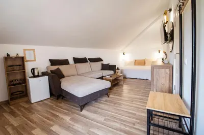 a living room with a couch and a bed at Къща за гости ЕМА in Vetren Dol