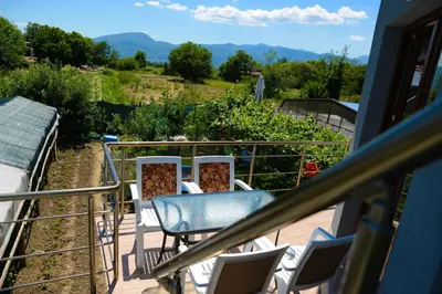 a balcony with chairs and a table and a garden at Къща за гости Хаджиеви in Ognyanovo