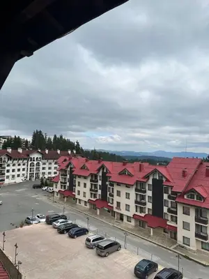 a group of buildings with cars parked in a parking lot at Art apartment Pamporovo Grand Monastery in Pamporovo