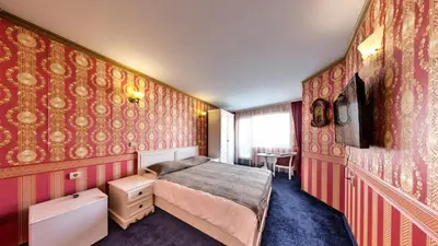 a bedroom with a bed and red wallpaper at Hotel Boyana in Sofia