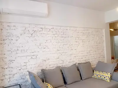 a couch with pillows against a white brick wall at Trendy and stylish in city centre for business and leisure in Sofia
