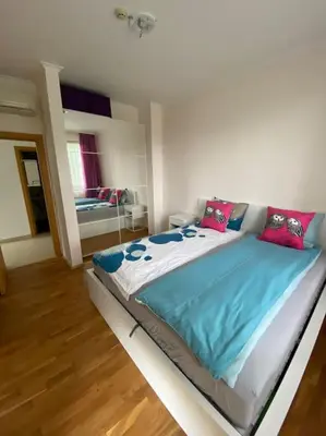 a bedroom with a large bed with blue sheets and pink pillows at Vacation house in Pravets golf resort At Pravets Lake in Pravets