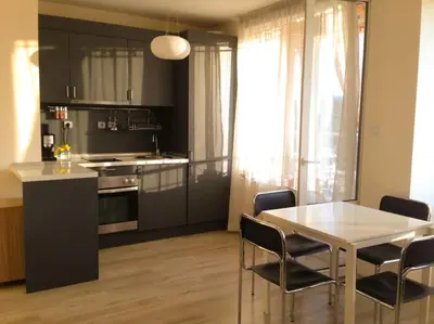 a kitchen with a table and some chairs and a table and a kitchen at Апартамент до парк и метро in Sofia