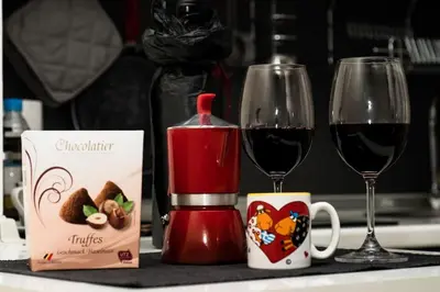 a table with two glasses of red wine and a coffee maker at Апартамент до парк и метро in Sofia