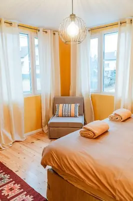 a bedroom with two beds and a chair and windows at Къща за гости РАДЕЯ in Govedartsi