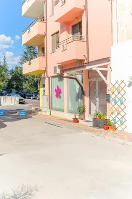 an empty parking lot in front of a pink building at Апартамент Амбра in Sandanski