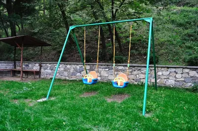 a swing set with three swings in a yard at Fisherman's Hut Family Hotel in Beden