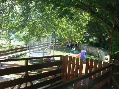 a wooden fence with a playground behind a tree at Fisherman's Hut Family Hotel in Beden