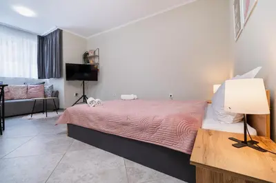 a bedroom with a bed with a pink bedspread at City Center Studio Apartments in Plovdiv
