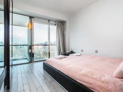 a bedroom with a large bed and large windows at Center Square Vitosha Blvd Panorama in Sofia