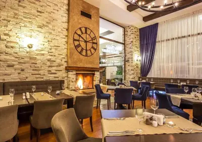 a restaurant with tables and chairs and a clock on the wall at Apartament by Zenit in Terra Complex Massonet D28 near Bansko in Razlog
