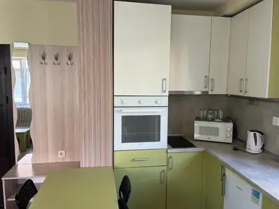 a kitchen with green cabinets and a table with a microwave at APARTHOTEL VICTORY SOFIA in Sofia