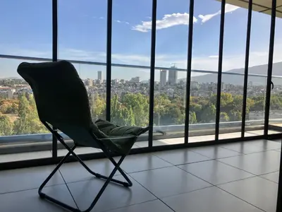 a green chair sitting in a room with a window at Point Sofia Grand Suite in Sofia