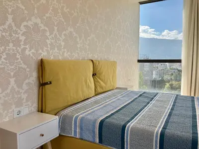 a bedroom with a bed with a yellow headboard and a window at Point Sofia Grand Suite in Sofia