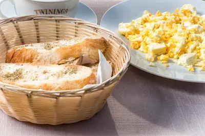 a basket of bread and a plate of scrambled eggs at Hotel Podkovata in Etropole