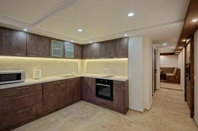 a large kitchen with wooden cabinets and a microwave at Къща за гости Relax in Hisarya