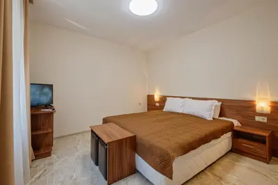 a bedroom with a large bed and a television at Къща за гости Relax in Hisarya