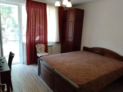 a bedroom with a bed and a large window at Цвят бяло in Sofia