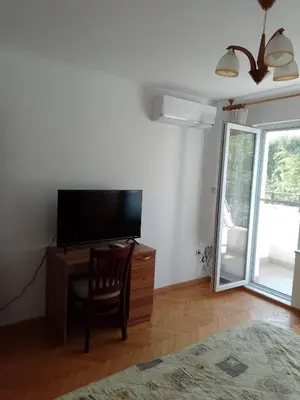 a living room with a television and a desk with a chair at Цвят бяло in Sofia