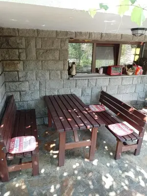two wooden benches sitting in front of a stone wall at Цвят бяло in Sofia