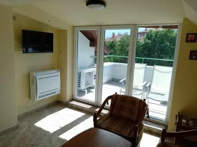 a living room with a chair and a large window at Цвят бяло in Sofia