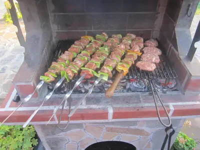a grill with meat and hamburgers on it at Guest House Popov in Marchevo