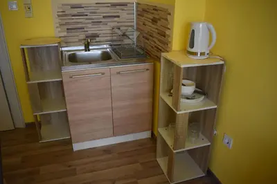 a small kitchen with a sink and wooden shelves at Apartment Airport Sofia in Sofia