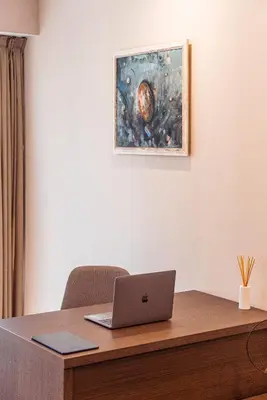 a laptop computer sitting on a wooden desk with a painting at Cityscape Luxury Suites in Plovdiv