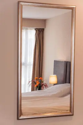 a mirror reflecting a bedroom with a bed and a window at Cityscape Luxury Suites in Plovdiv
