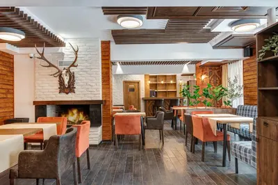 a restaurant with tables and chairs and a fireplace at Къща за гости Чудните Мостове in Zabŭrdo