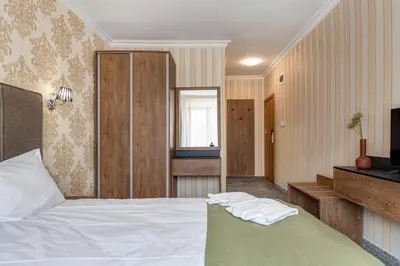 a bedroom with a white bed and a television at Къща за гости Чудните Мостове in Zabŭrdo