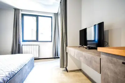 a hotel room with a bed and a flat screen tv at 6 Studios 6 Bathrooms 2 Levels Kitchens in Sofia