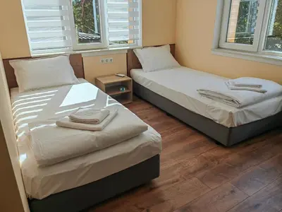 two twin beds in a room with two windows at стаи за гости TODA in Troyan