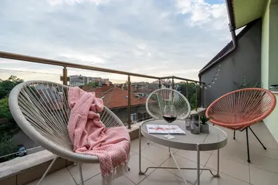a balcony with two chairs and a table with a glass of wine at Three Lilies Apartments in Plovdiv
