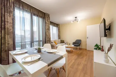 a living room with a table and chairs in a room at Three Lilies Apartments in Plovdiv