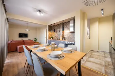 a dining room and living room with a wooden table and chairs at Three Lilies Apartments in Plovdiv