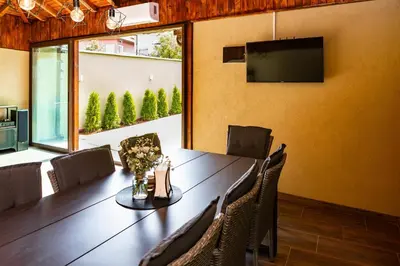 a dining room with a table and chairs and a television at Forest Oasis Guest House FREE PARKING in Sapareva Banya