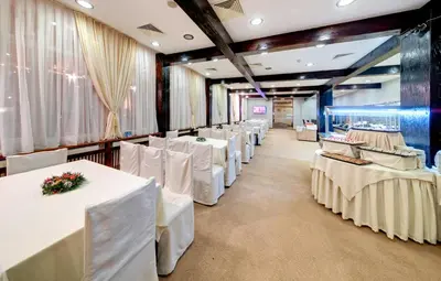 a row of white tables and chairs in a room at Hotel Panorama Ski in Pamporovo
