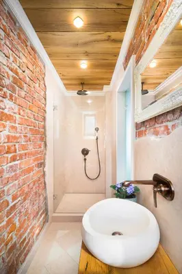 a bathroom with a white sink and a brick wall at Alexandra's City Center Apartment II in Sofia