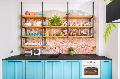 a kitchen with blue cabinets and a brick wall at Alexandra's City Center Apartment II in Sofia