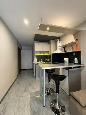 a kitchen with a counter and stools in a room at Апартаменти в сърцето на парка in Sandanski