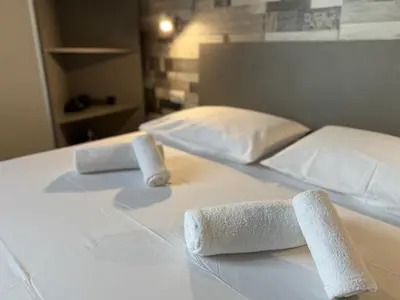 two rolled up towels on a white bed at Апартаменти в сърцето на парка in Sandanski