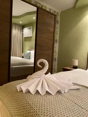 a towel swan sitting on a bed in front of a mirror at Eda Aparts in Devin