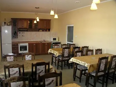 a dining room with tables and chairs and a kitchen at Karadzhovy Guest House in Kalofer