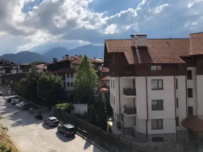a building with cars parked in a parking lot at Simon1 studio, 2 min to gondola in Bansko