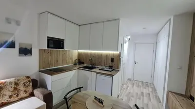 a kitchen with white cabinets and a table in a room at Monfort В in Bansko