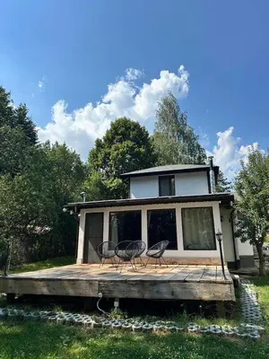 a house with two chairs on a wooden deck at Villa Yarema Mountain Relax with Hot Jacuzzi & Sauna by BookVillaBG in Zheleznitsa