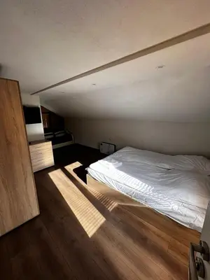 a bedroom with a white bed and a wooden floor at Райски кът “Еленова поляна” in Dobărsko