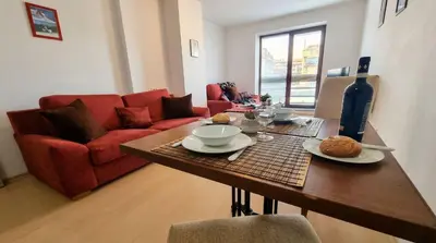 a living room with a table and a red couch at Mountain Paradise 4 - 1 Bedroom - Gondola, 100m away - Washer in Bansko